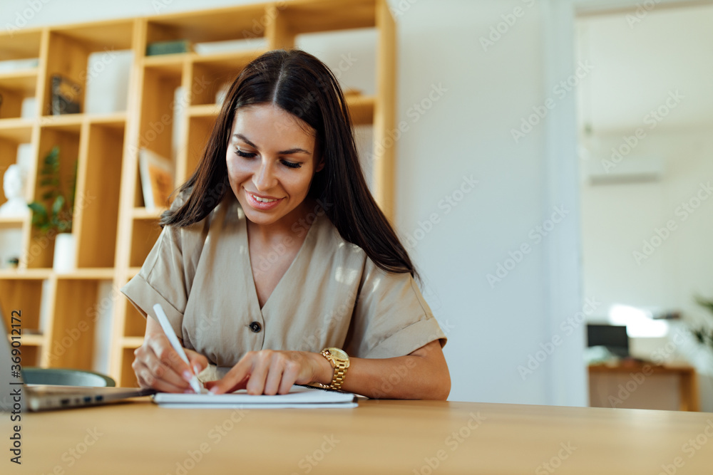 Business woman hand writing with a pen in the home office.