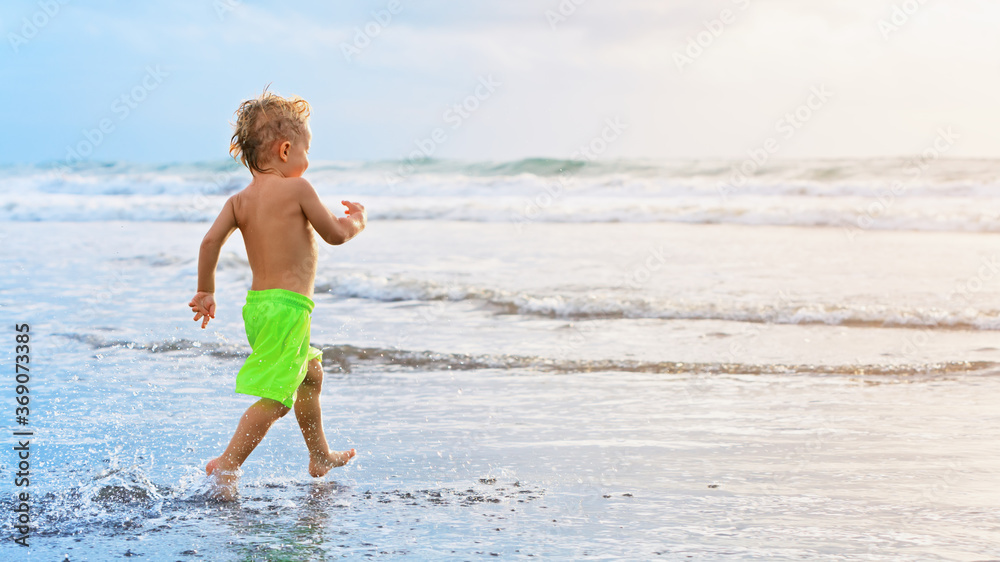 Happy family have fun on tropical sea beach resort. Funny baby boy run with splashes by water pool a