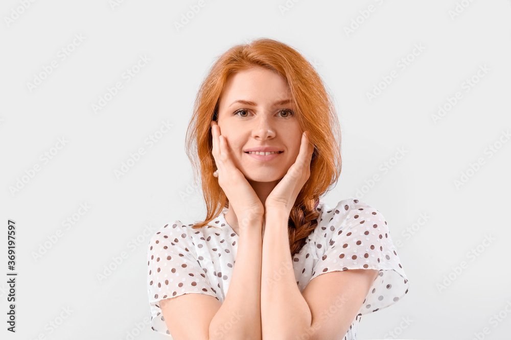 Beautiful young redhead woman on light background