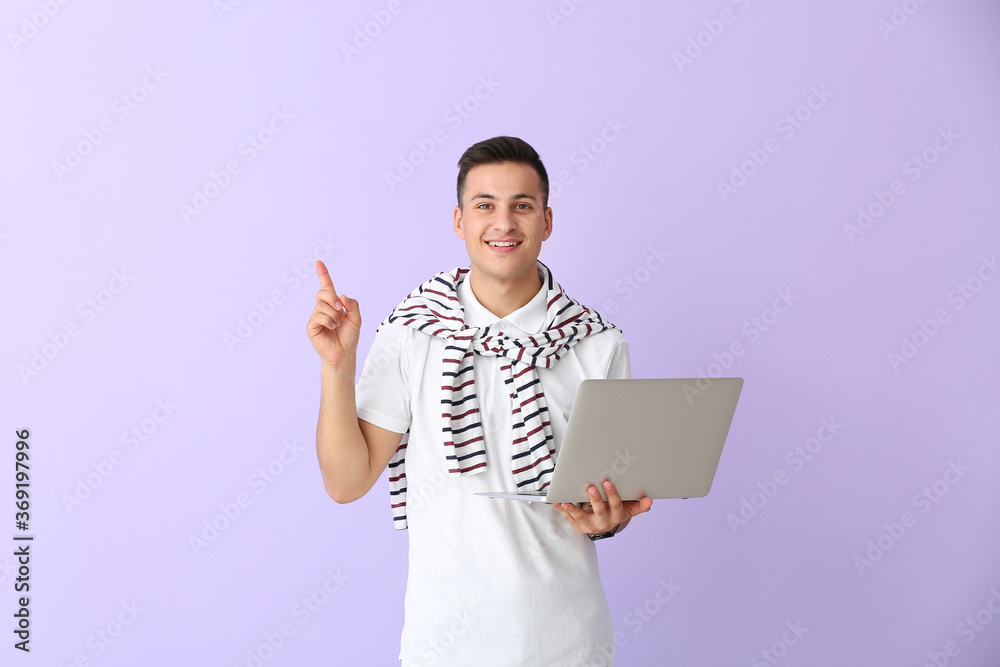 Male programmer with laptop and raised index finger on color background