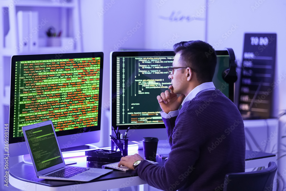 Male programmer working in office at night