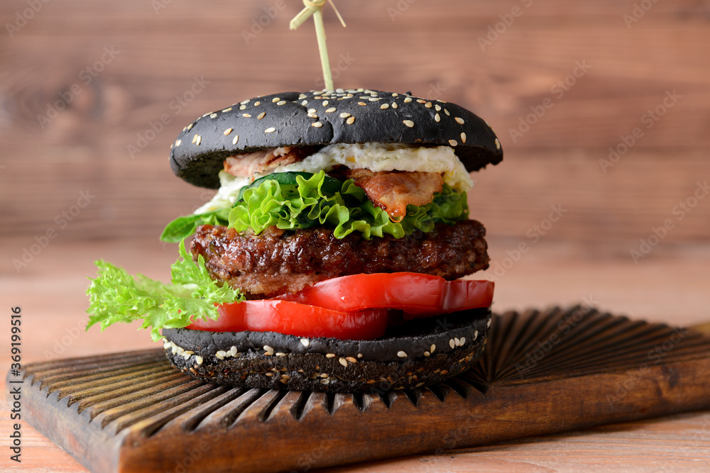 Tasty burger with black bun on table