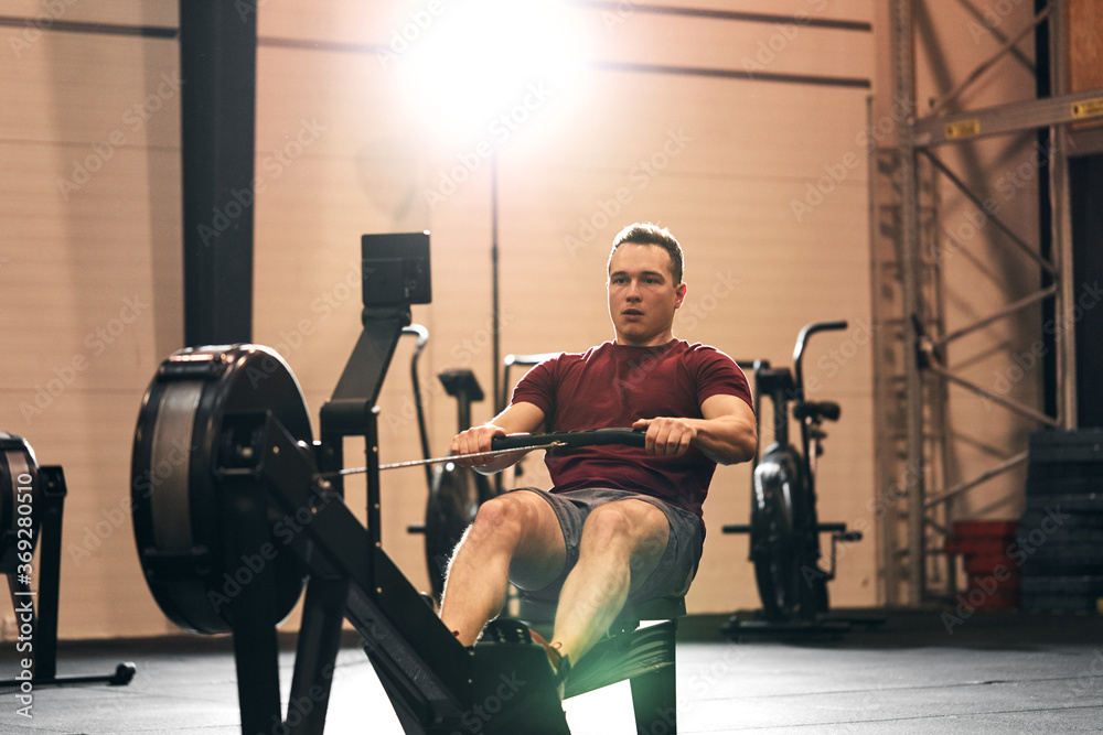 Young man exercising on a gym rowing machine