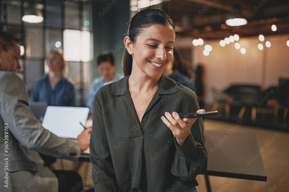 Young businesswoman smiling while talking on speakerphone in an