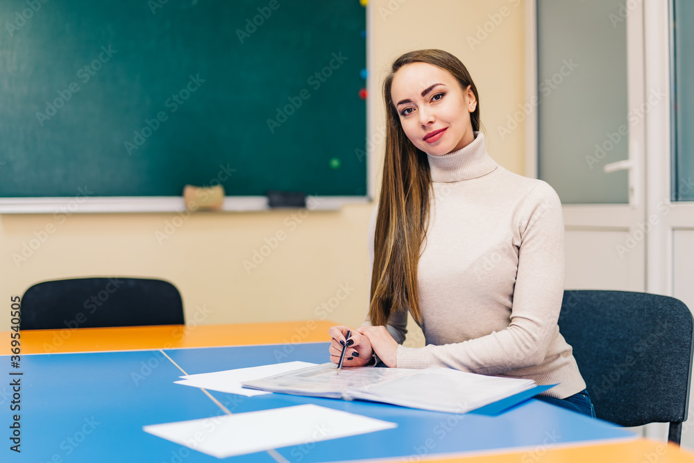 Beautiful school teacher sitting in the classroom. Progressive school. Education, school, learning.