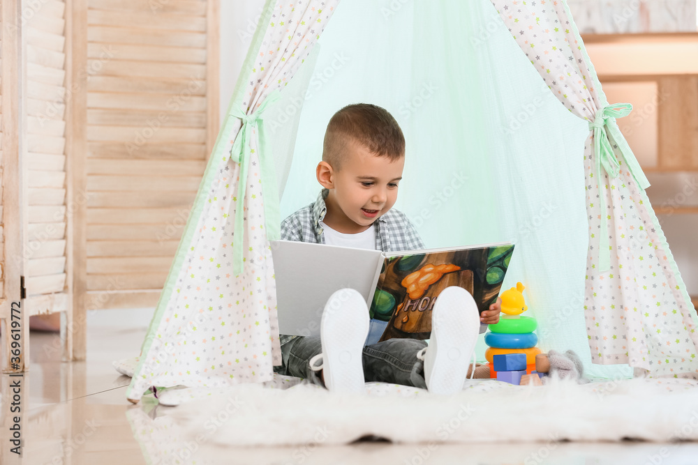 Cute little boy reading book at home