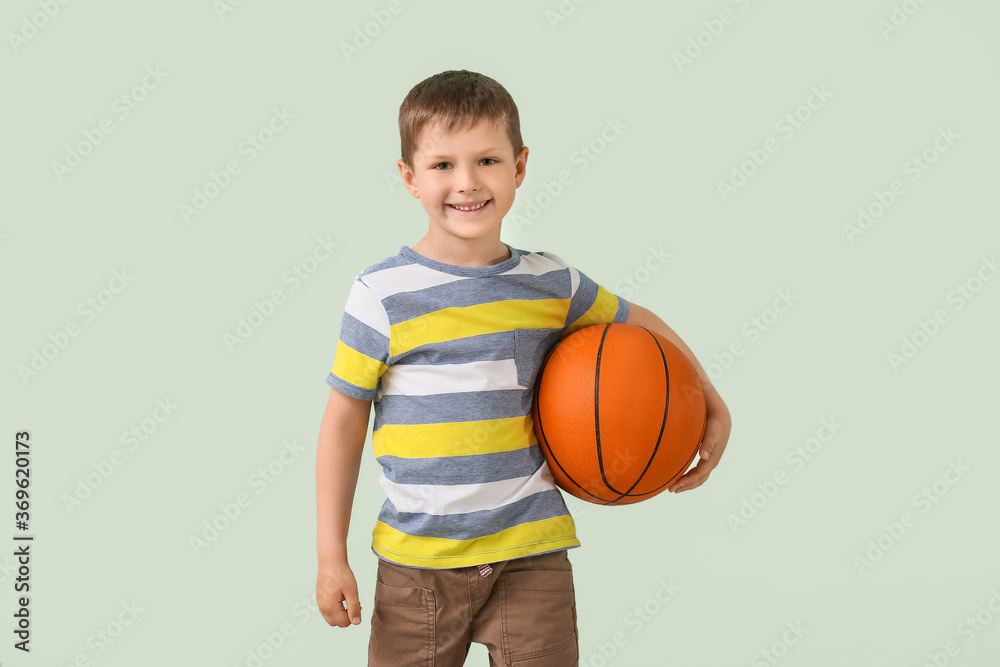 Cute little boy with ball on color background