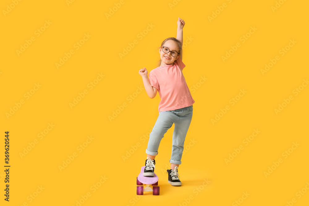 Cute little girl with skateboard on color background