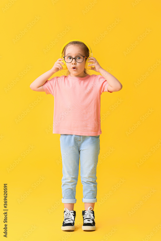 Cute little girl listening to music on color background