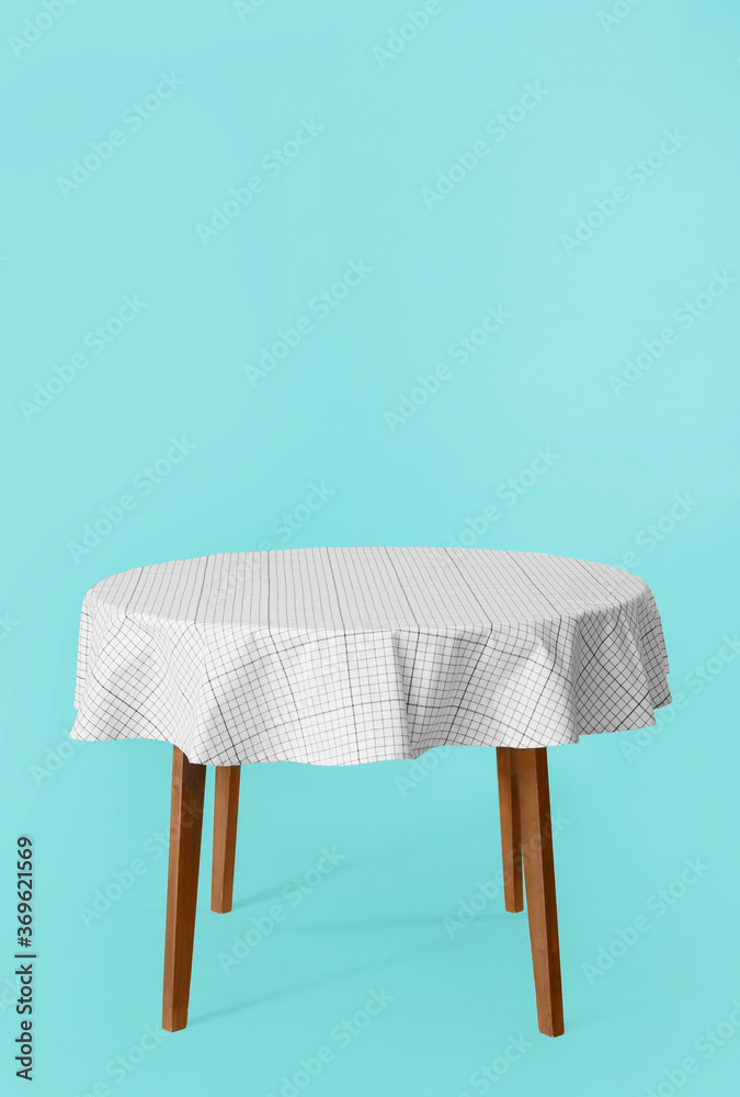 Dining table with tablecloth on color background