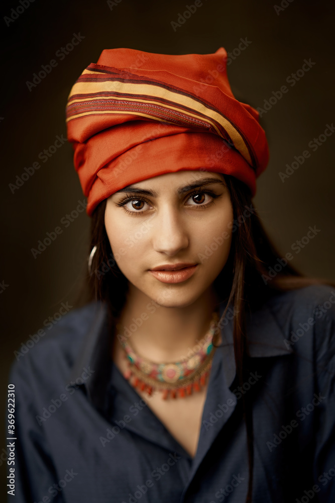 Art portrait of young beautiful girl in a red turban. Central Asian or oriental style, tradition and