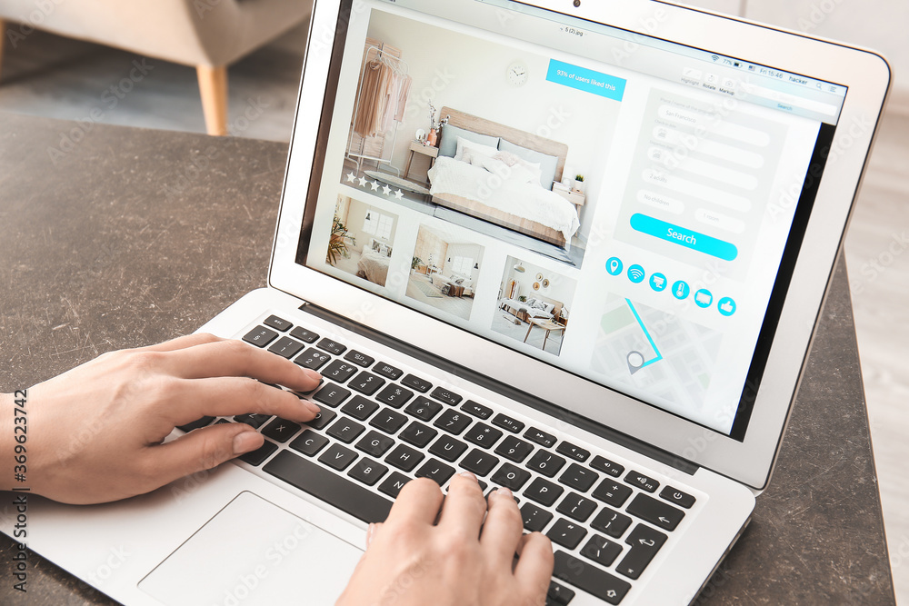 Woman with laptop booking room in hotel online at home