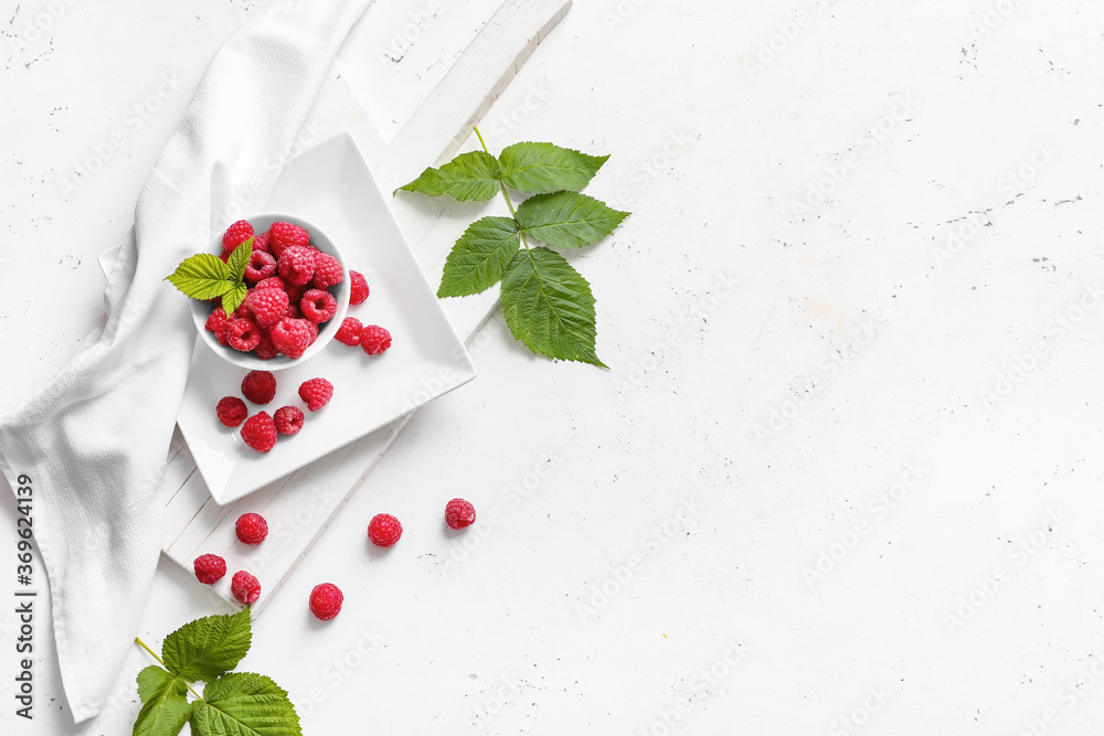 Bowl with ripe raspberries on white background