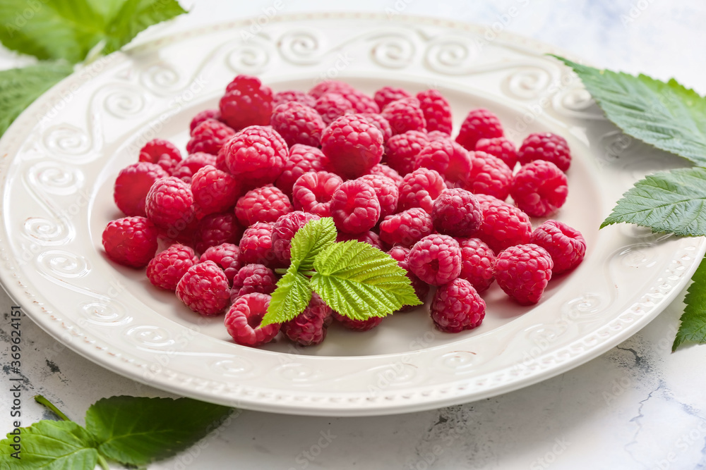 Plate with ripe raspberries on table, closeup