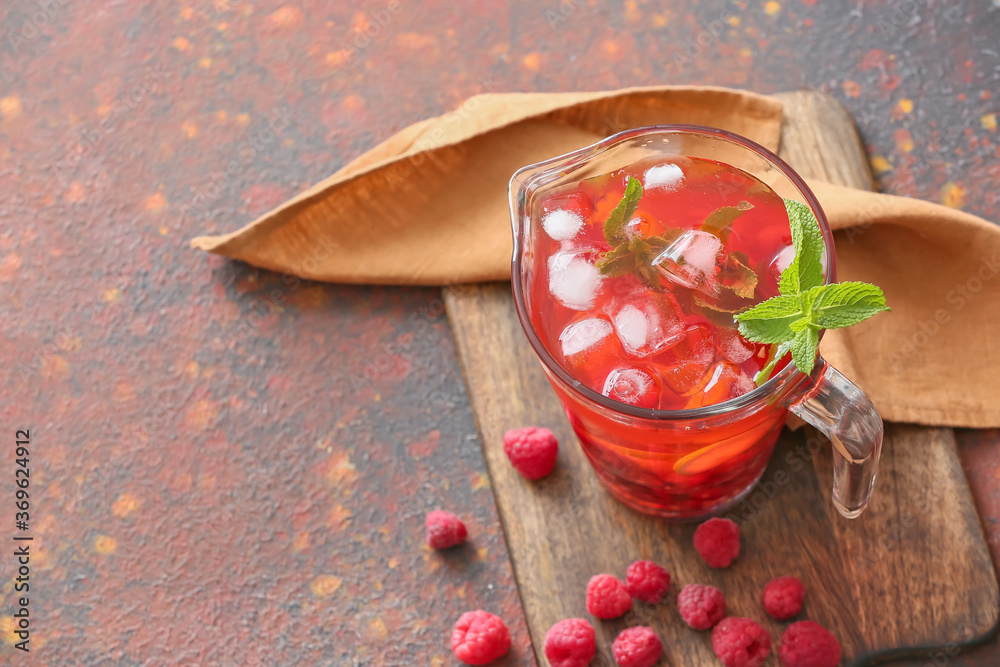 Jug of cold raspberry tea on color background