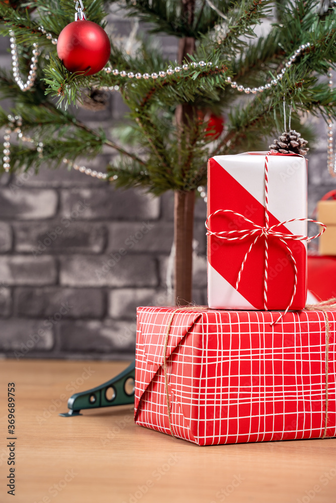 Decorated Christmas tree with wrapped beautiful red and white gifts at home with black brick wall, f