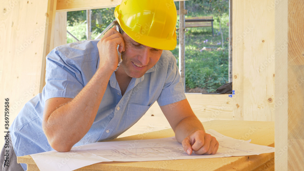 CLOSE UP: Architect is satisfied as he talks on the phone about the floor plans.