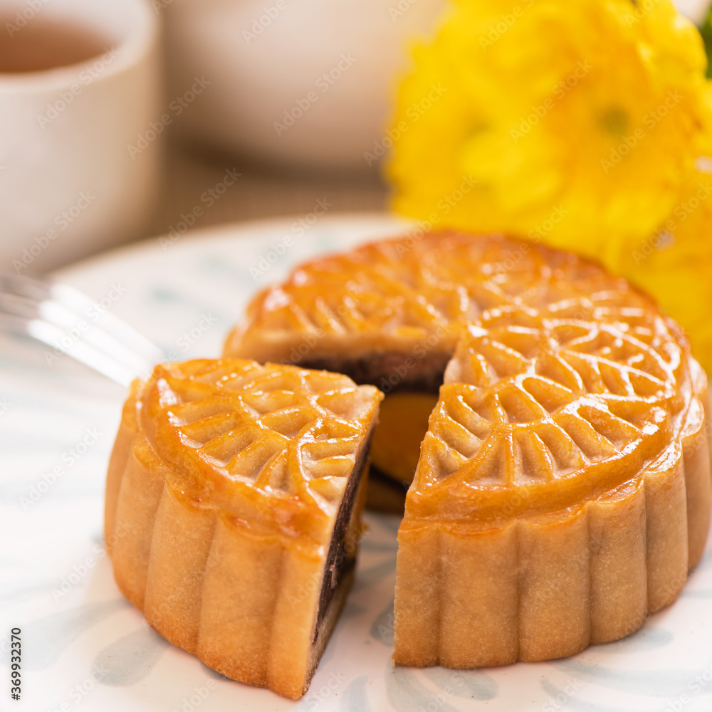 Tasty baked egg yolk pastry moon cake for Mid-Autumn Festival on bright wooden table background. Chi