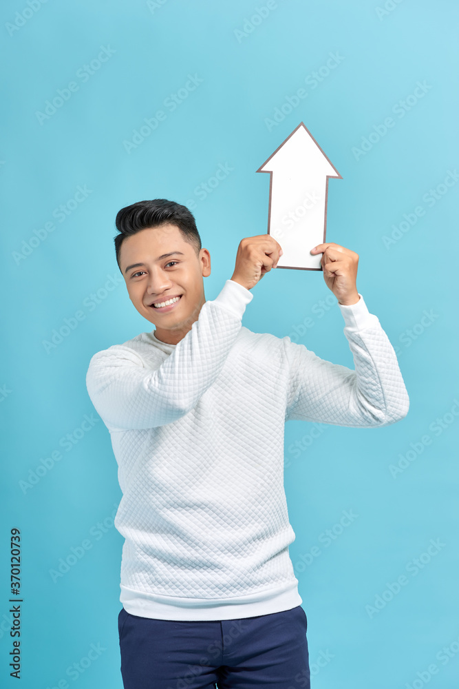 young man raises white arrow isolated on blue