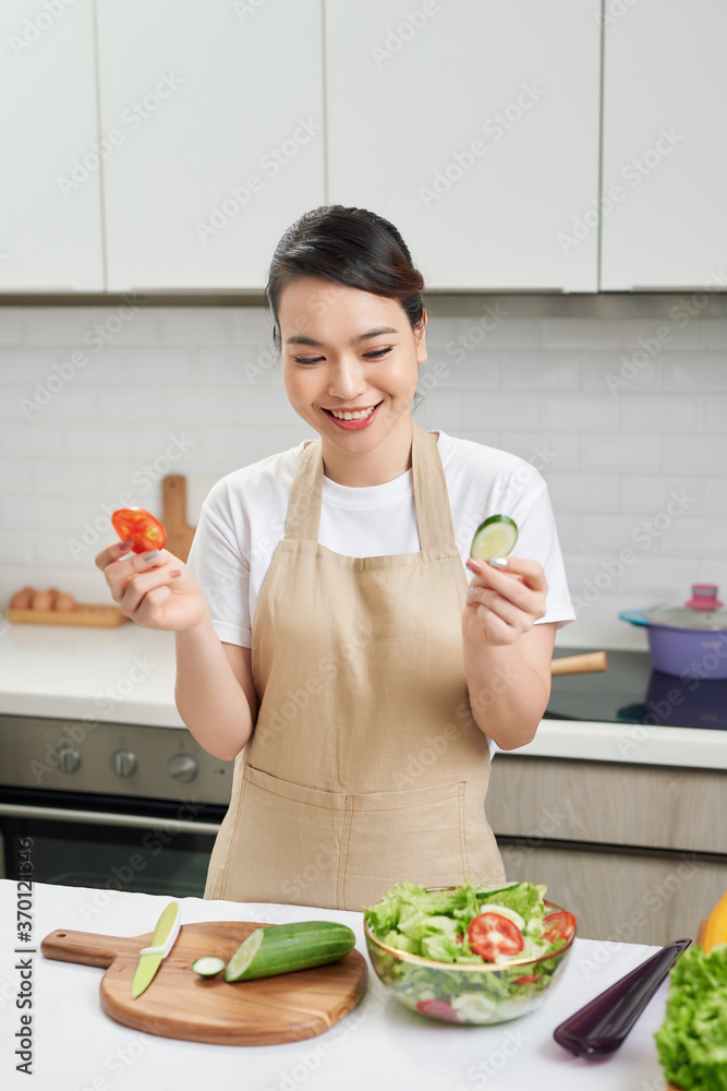 Young woman preparing vegetable salad in the kitchen