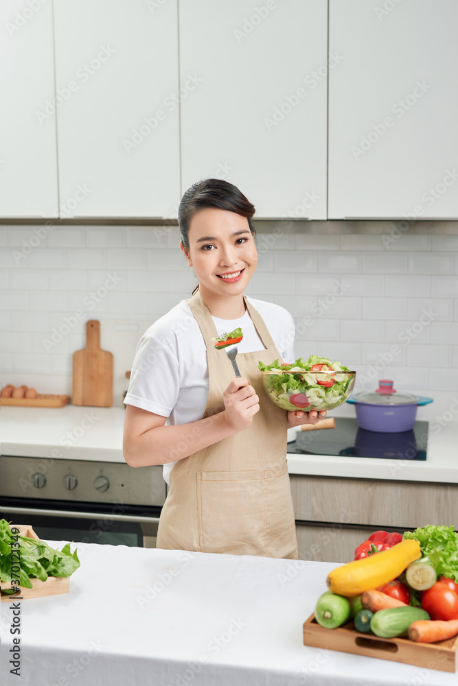 Vertical photo of a young woman who eats salad at home, a concept diet