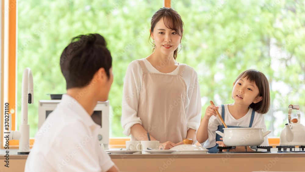 キッチンで料理を作る女の子と両親