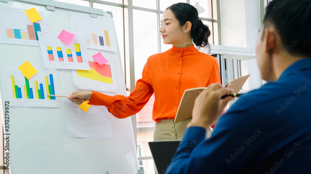 Young woman explains business data on white board in casual office room . The confident Asian busine