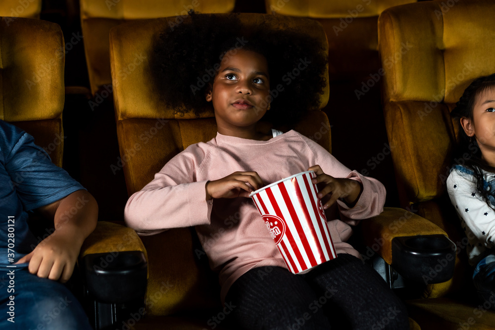 Three children having fun and enjoy watching movie in cinema