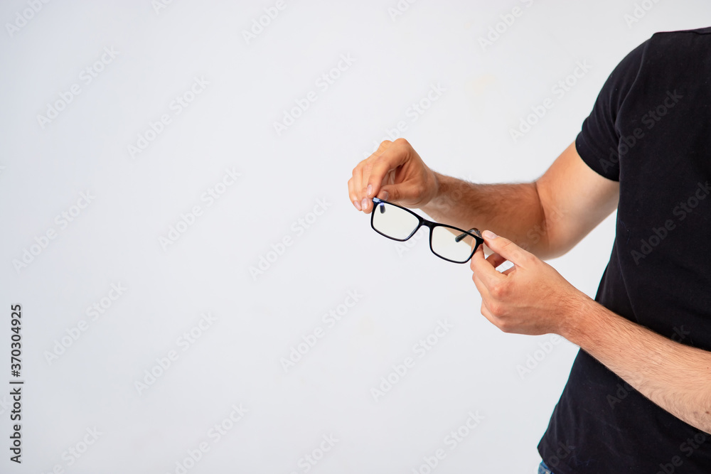 Man s hands holds trendy glasses with black rim on a white background in the studio. Close-up