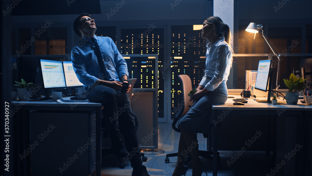 Late at Night in the Corporate Office Two Young Professionals Chatting Friendly, Exchanging News, Ta