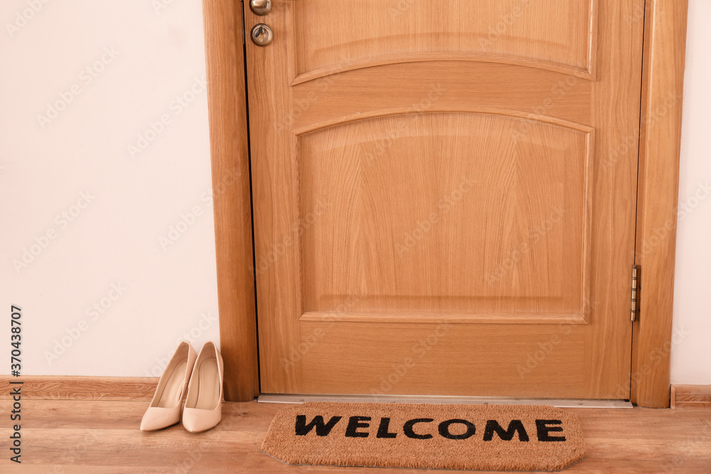 Door mat and female shoes on floor in hallway