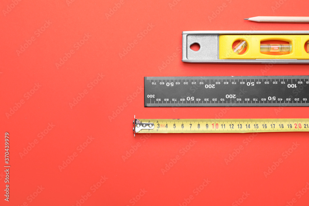 Measuring tape with builders supplies on color background