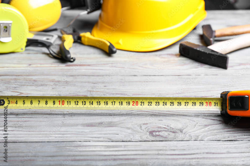 Measuring tape with builders supplies on wooden background