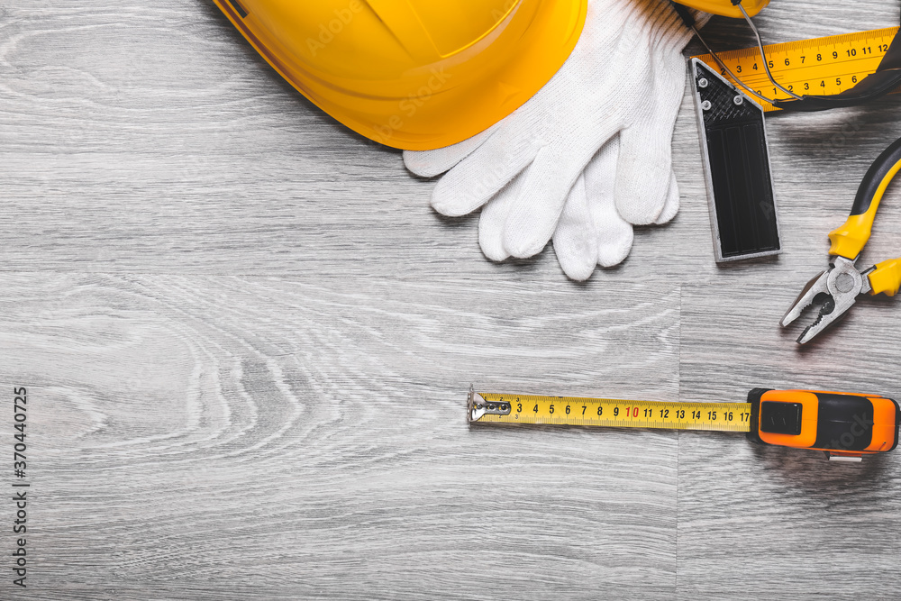 Measuring tape with builders supplies on wooden background