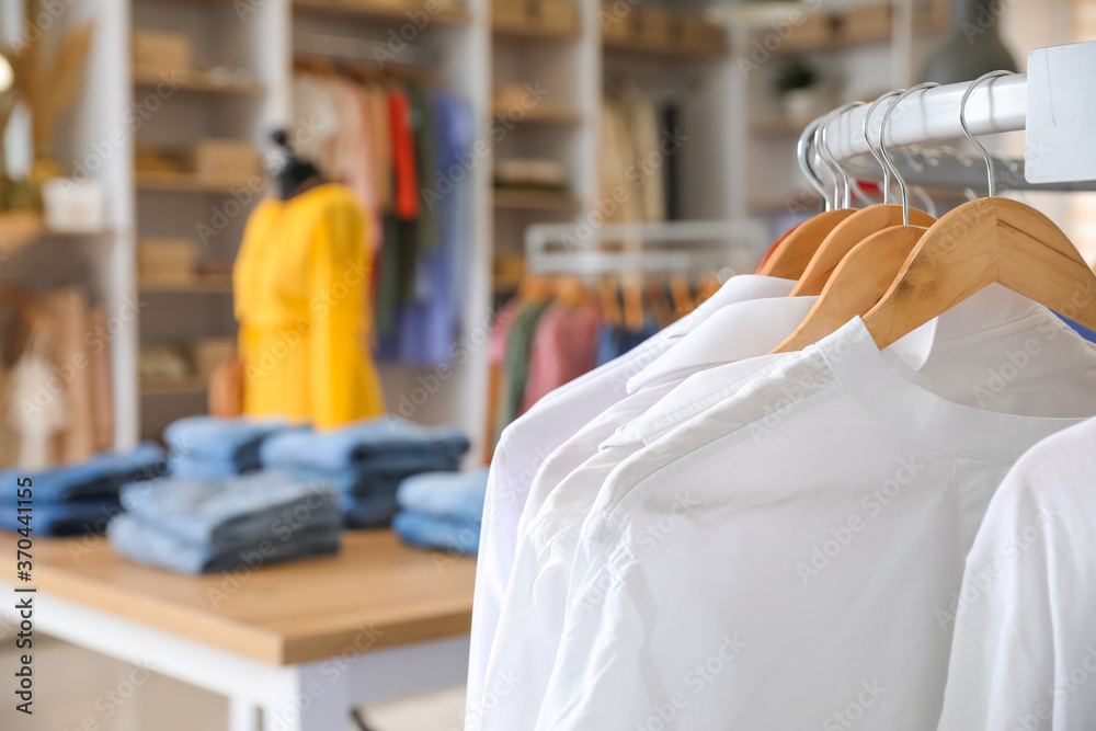 Hanger with stylish clothes in modern store, closeup