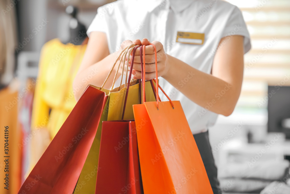 Female seller with shopping bags in modern clothes store