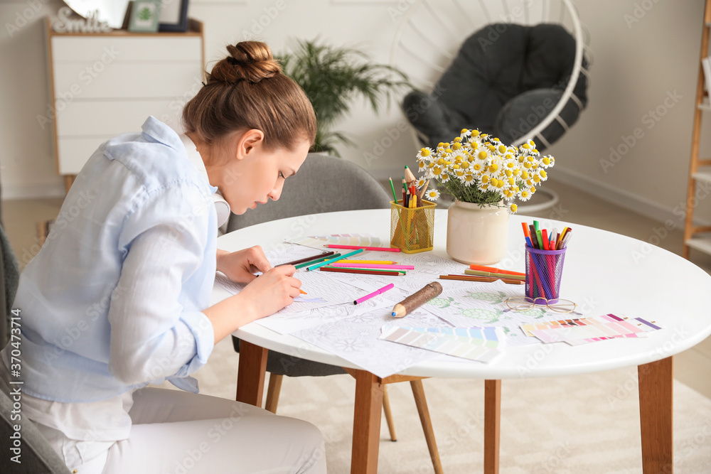 Young woman coloring picture at home