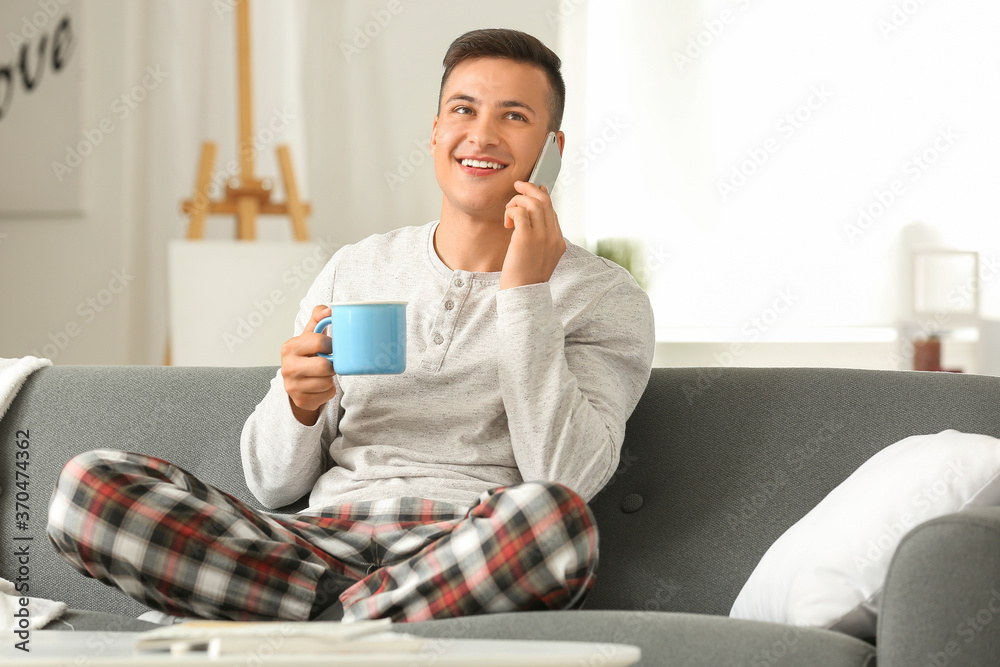 英俊的年轻人在家喝茶时打电话