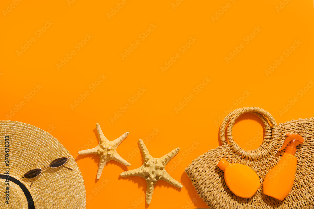 Beach bag with sunscreen cream and accessories on color background