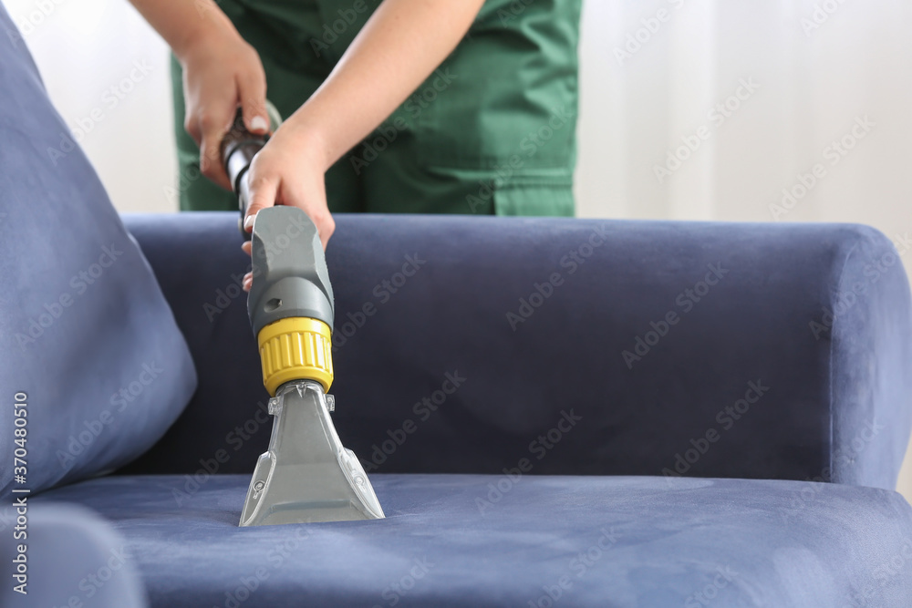 Dry cleaners employee removing dirt from sofa in house