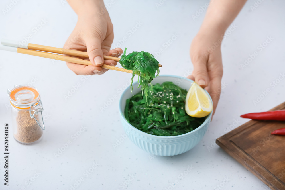 女人在餐桌上吃美味的海藻沙拉