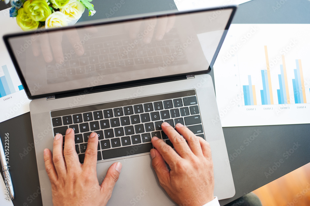 Business people work on laptops on their desks.