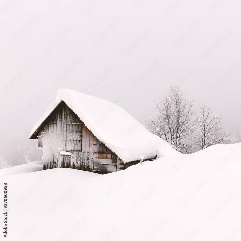 雪山木屋的极简主义冬季景观。多云，景观照片