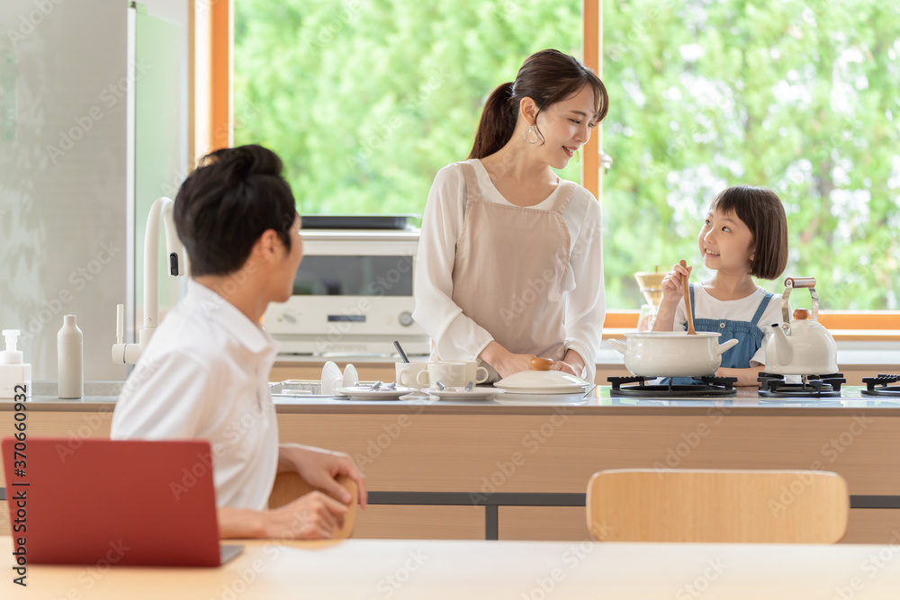 キッチンで働くお父さんと見守る親子