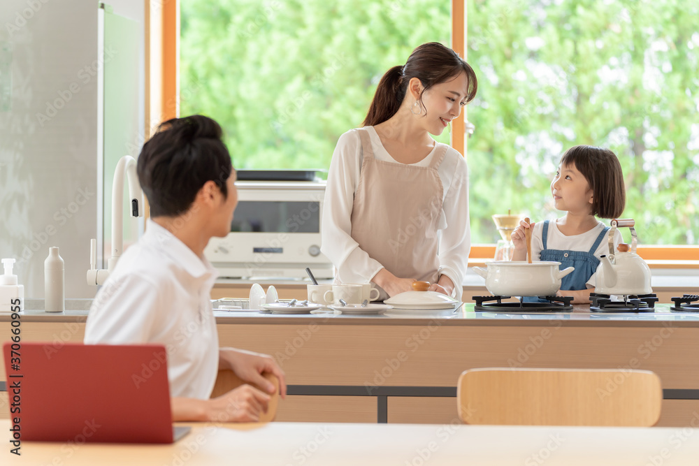 キッチンで働くお父さんと見守る親子