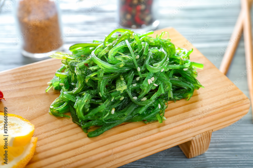 Board with tasty seaweed salad on table, closeup