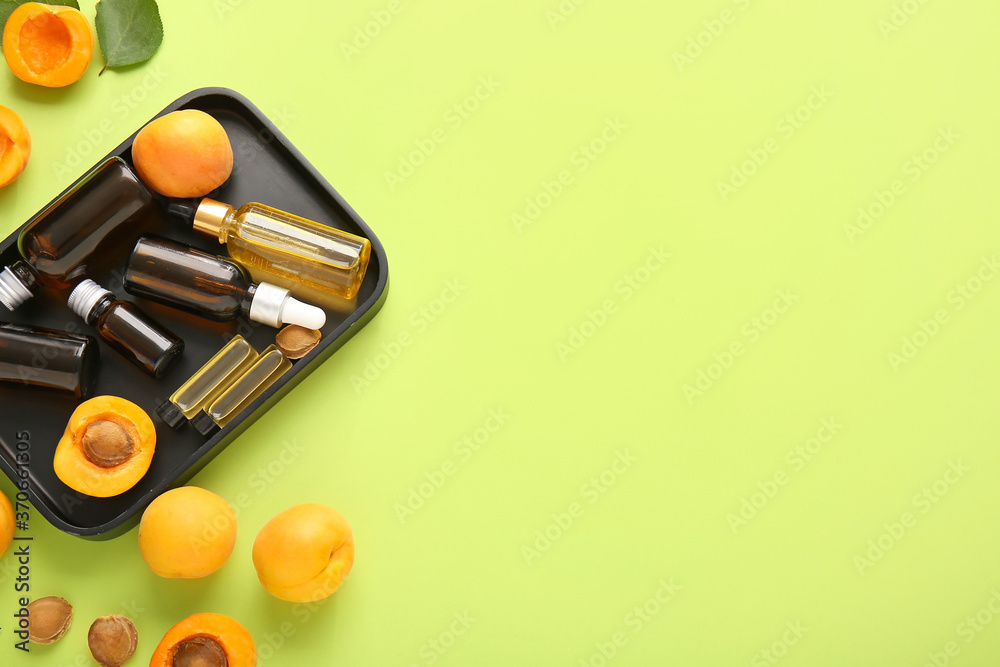 Bottles of apricot essential oil on color background