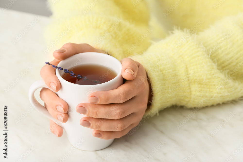 Woman with cup of hot tea at table, closeup