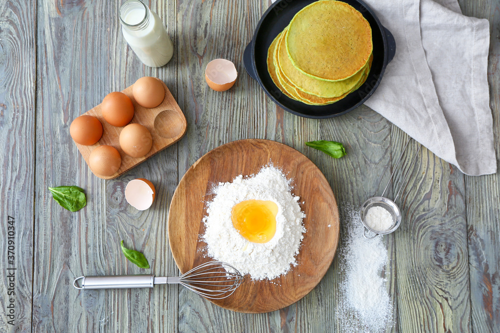 Tasty green pancakes with ingredients on table