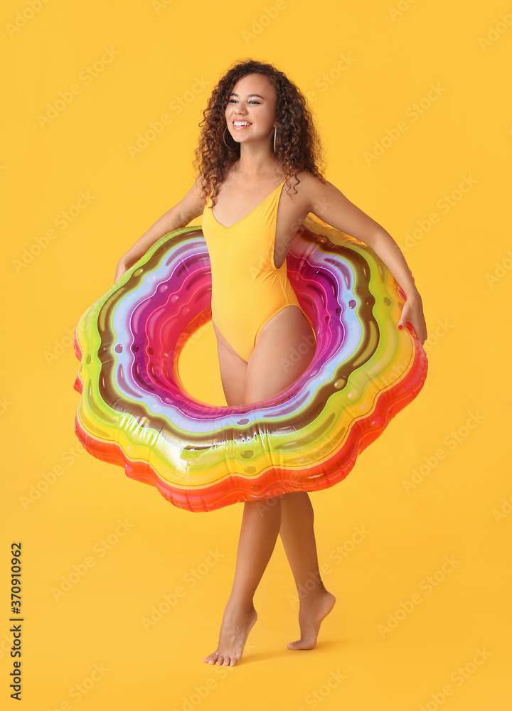 Beautiful young African-American woman with inflatable ring on color background